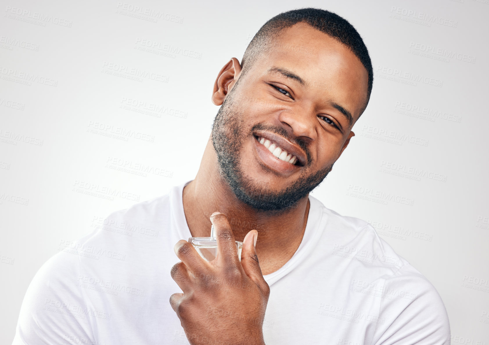 Buy stock photo Studio portrait of a handsome young man spraying perfume on himself against a white background