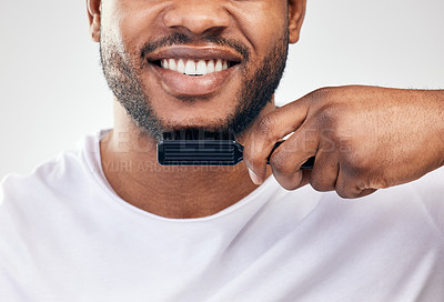 Buy stock photo Studio shot of a young man brushing his facial hair against a white background