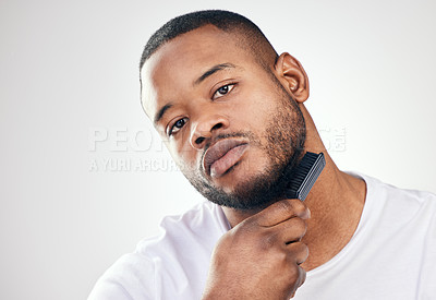 Buy stock photo Studio portrait of a handsome young man brushing his facial hair against a white background