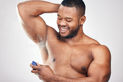 Buy stock photo Studio shot of a handsome young man spraying deodorant on his armpit against a white background