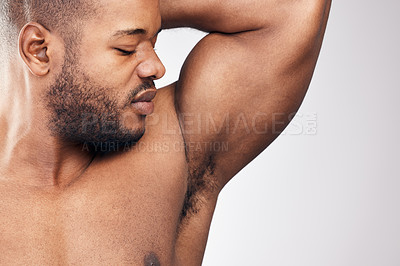 Buy stock photo Studio shot of a handsome young man smelling his armpit against a white background