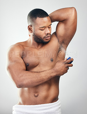 Buy stock photo Studio shot of a handsome young man spraying deodorant on his armpit against a white background