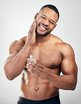 Buy stock photo Studio portrait of a handsome young man applying aftershave to his face against a white background