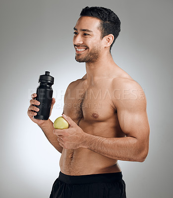 Buy stock photo Shot of a man standing against a grey background while holding a bottle of water and an apple
