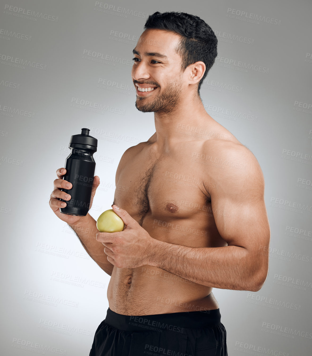 Buy stock photo Water bottle, apple and man in studio with fitness, exercise and healthy diet for nutrition. Smile, workout and shirtless male athlete with h2o drink and fruit for hydration by gray background.