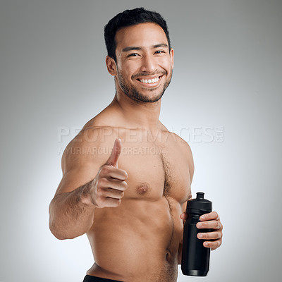 Buy stock photo Shot of an athletic man holding a bottle of water while standing against a grey background