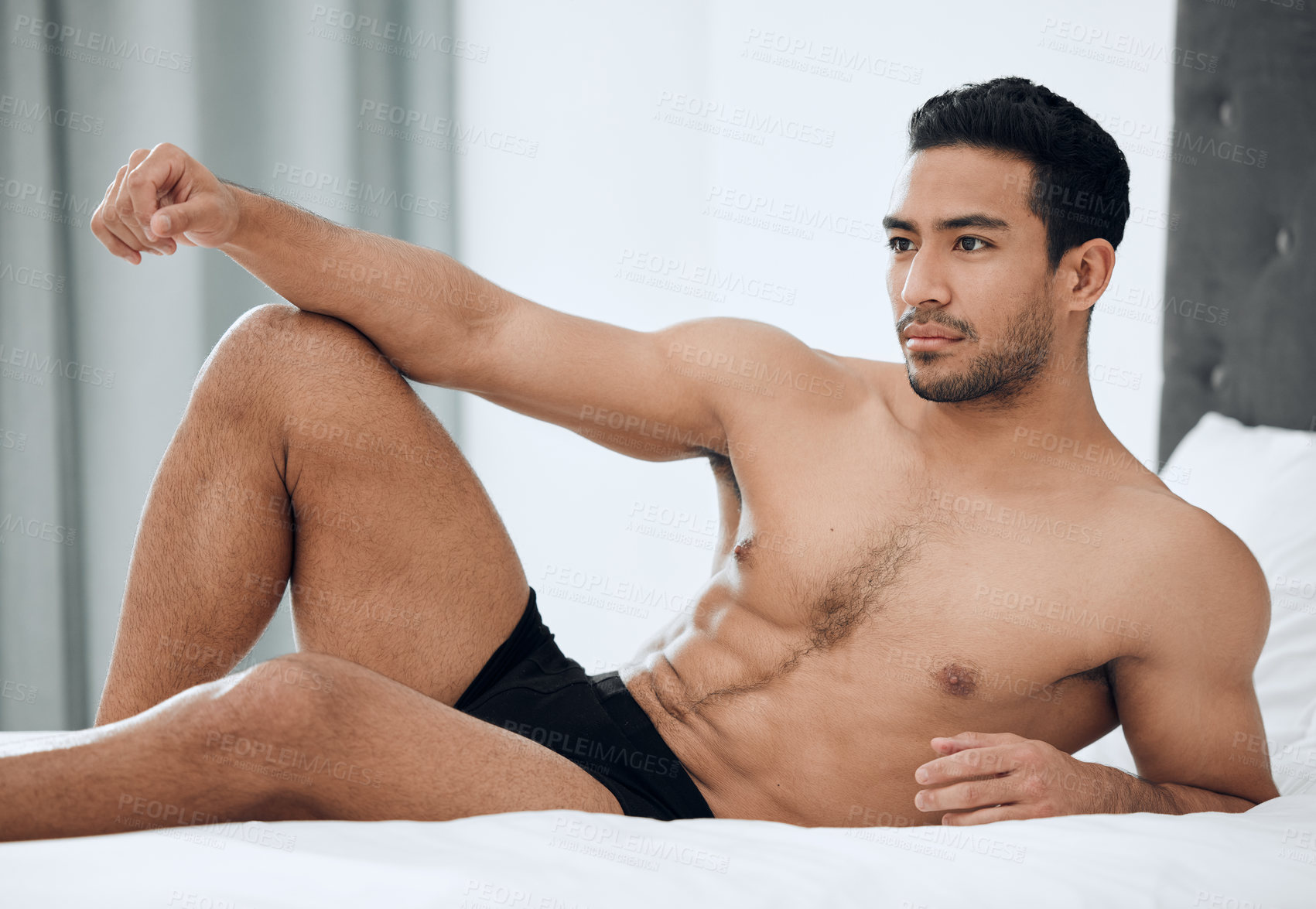 Buy stock photo Shot of a handsome young man lying on his bed