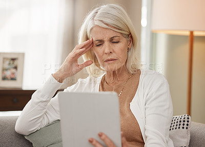 Buy stock photo Shot of a mature woman using a digital tablet and feeling unwell at home