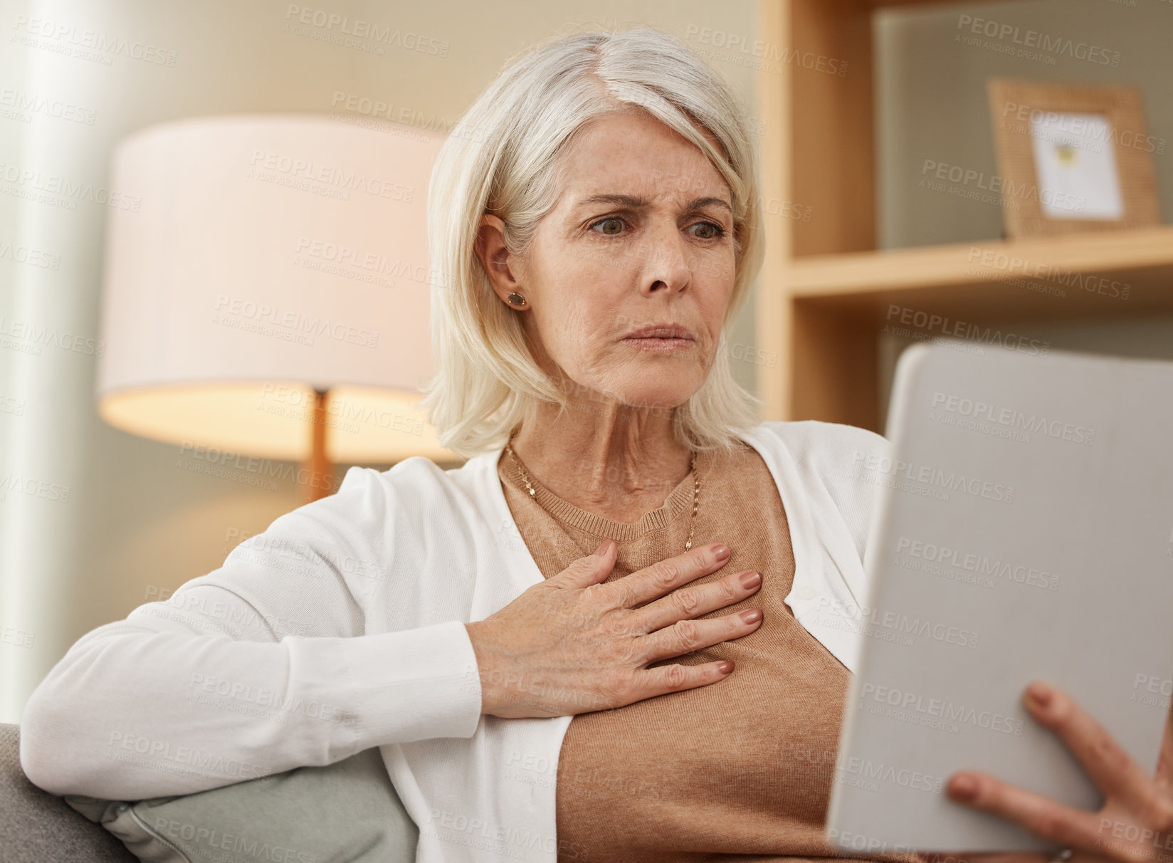 Buy stock photo Bad news, shock and tablet with senior woman on sofa in living room of retirement home for research. Alert, notification and technology with elderly person reading information or gossip on internet