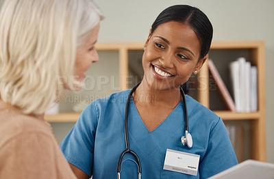 Buy stock photo Shot of a doctor using a digital tablet during a consultation with a senior woman at home