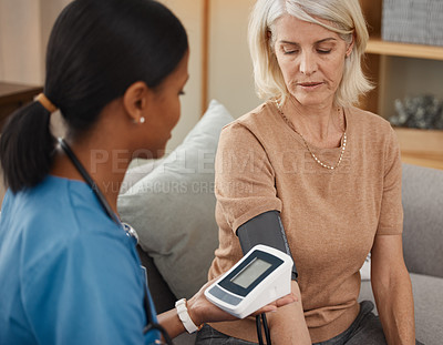 Buy stock photo Shot of a doctor examining a senior woman with a blood pressure gauge at home