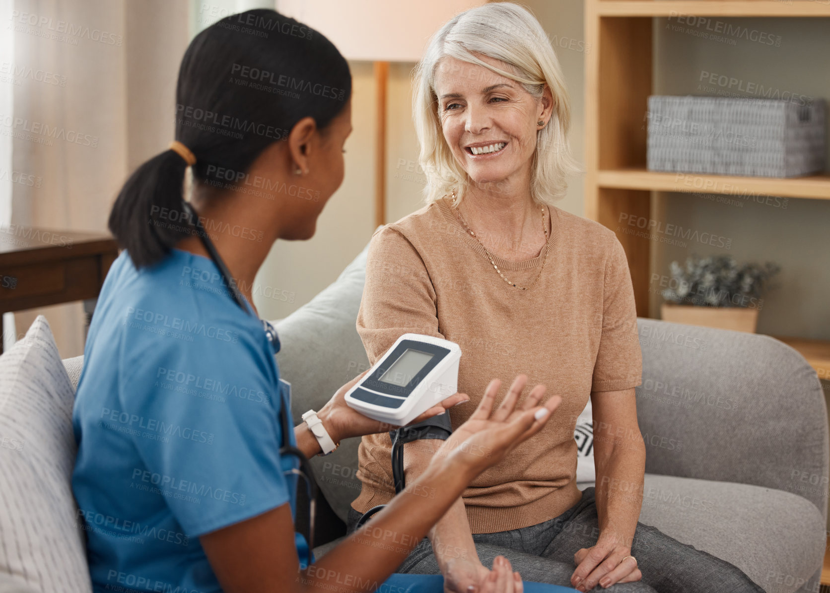 Buy stock photo Shot of a doctor examining a senior woman with a blood pressure gauge at home