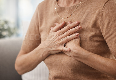 Buy stock photo Shot of an unrecognisable woman experiencing chest pain at home