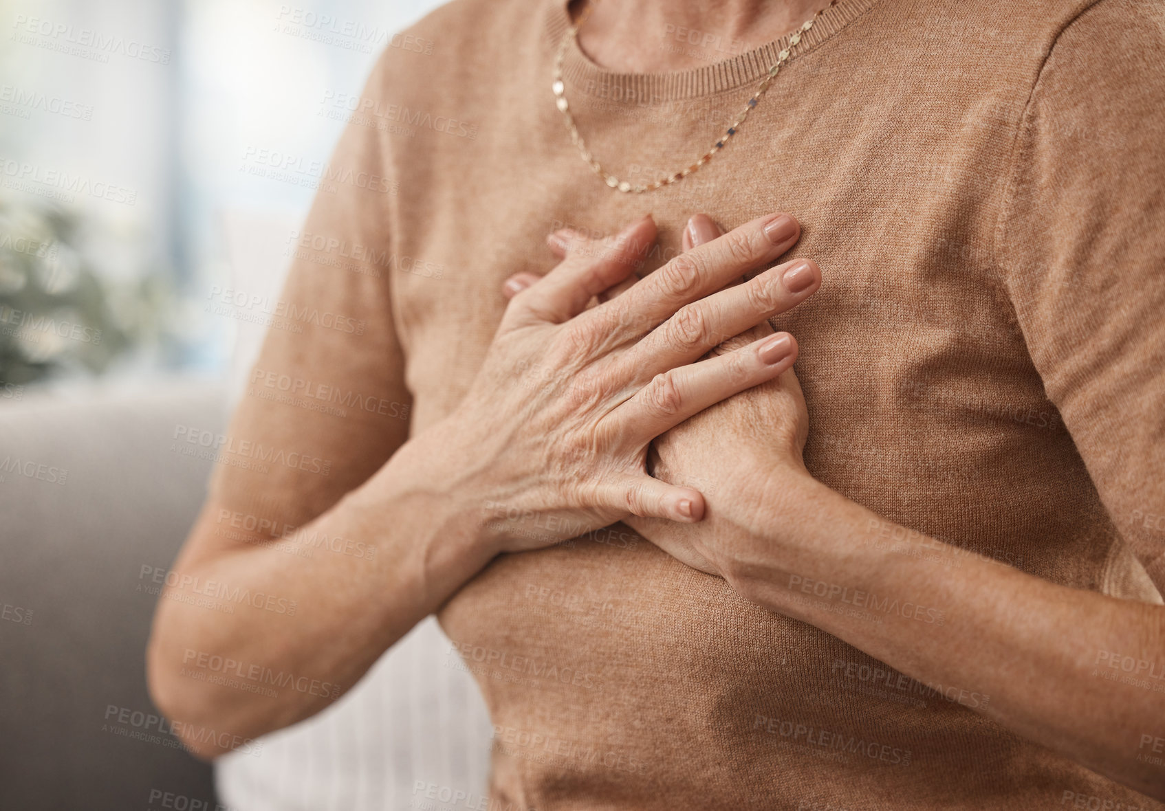 Buy stock photo Shot of an unrecognisable woman experiencing chest pain at home