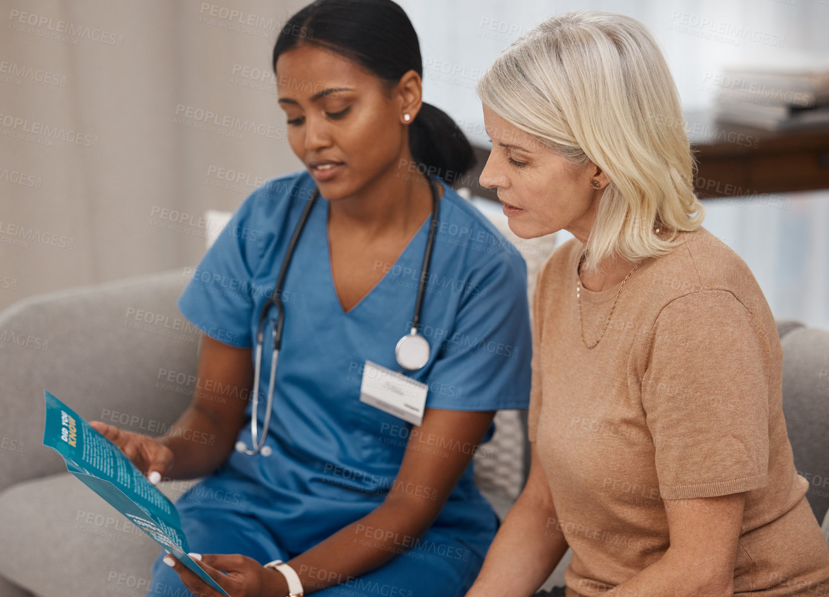 Buy stock photo Shot of a doctor reading a pamphlet about Covid-19 on the sofa at home