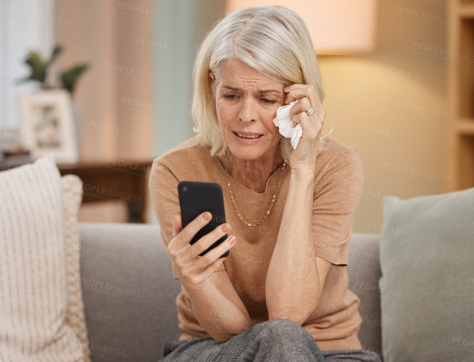 Buy stock photo Smartphone, crying and mature woman in home with communication and reading text for cancer diagnosis. Mobile, stress or fear and senior person with tears for mental health and medical crisis on sofa