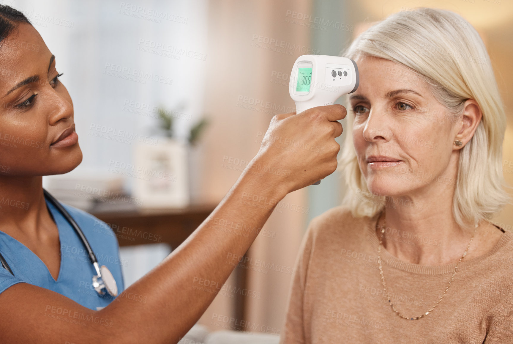 Buy stock photo Shot of a doctor examining a mature woman with a thermometer at home