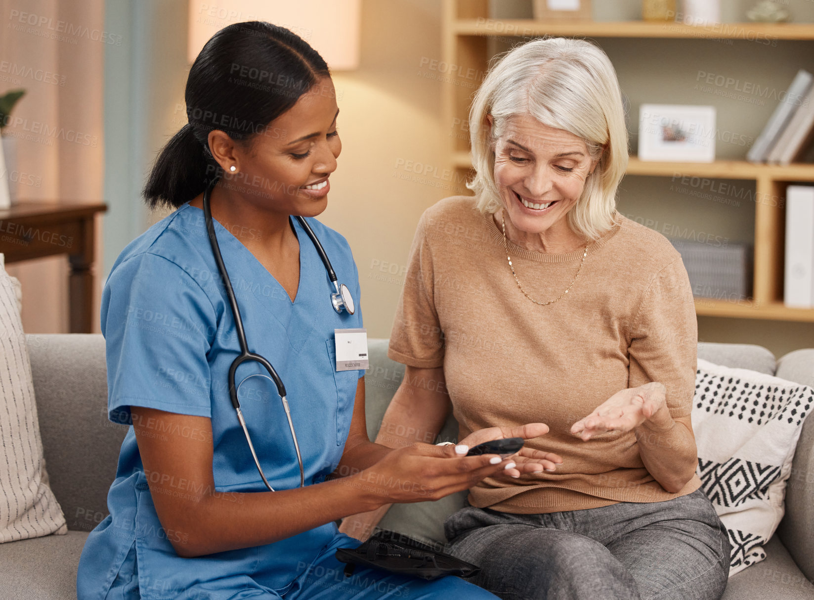 Buy stock photo Shot of a doctor using a smartphone during a consultation with a senior woman at home