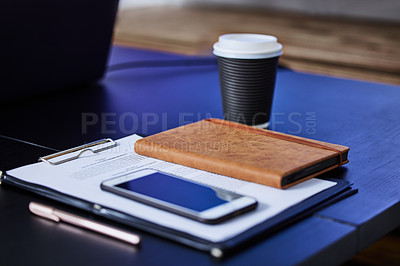 Buy stock photo Closeup shot of a cellphone, diary and paperwork on a table in an office