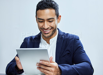 Buy stock photo Shot of a young  businessman using a digital tablet against a white background