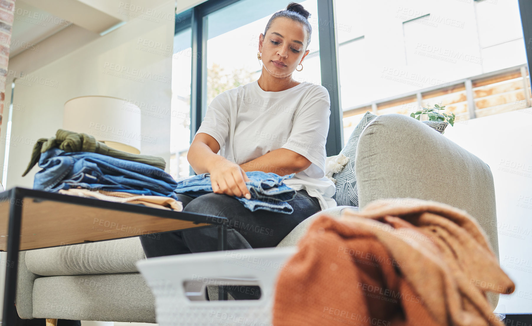 Buy stock photo Shot of a young woman folding a load of laundry