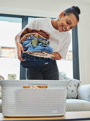 Buy stock photo Shot of a young woman packing away clean laundry