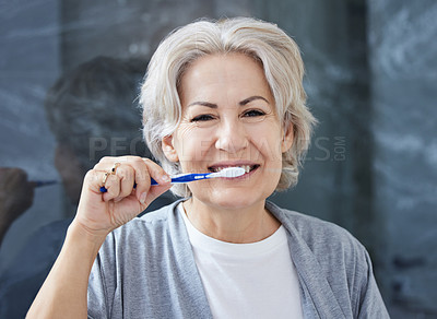 Buy stock photo Shot of a senior woman brushing her teeth at home