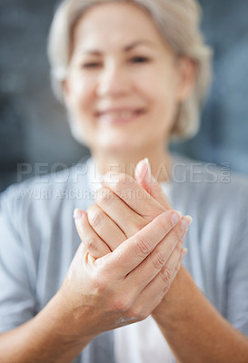 Buy stock photo Shot of a senior woman applying moisturiser to her hands