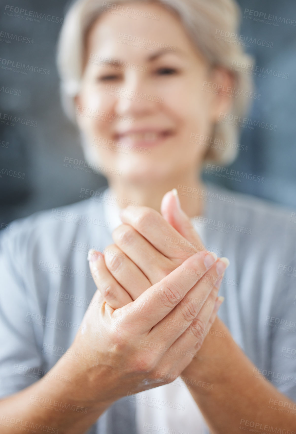 Buy stock photo Shot of a senior woman applying moisturiser to her hands