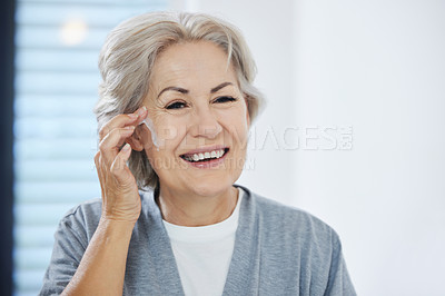 Buy stock photo Shot of a senior woman going through her skincare routine at home