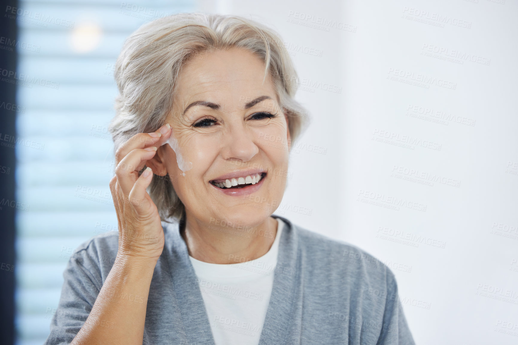 Buy stock photo Shot of a senior woman going through her skincare routine at home