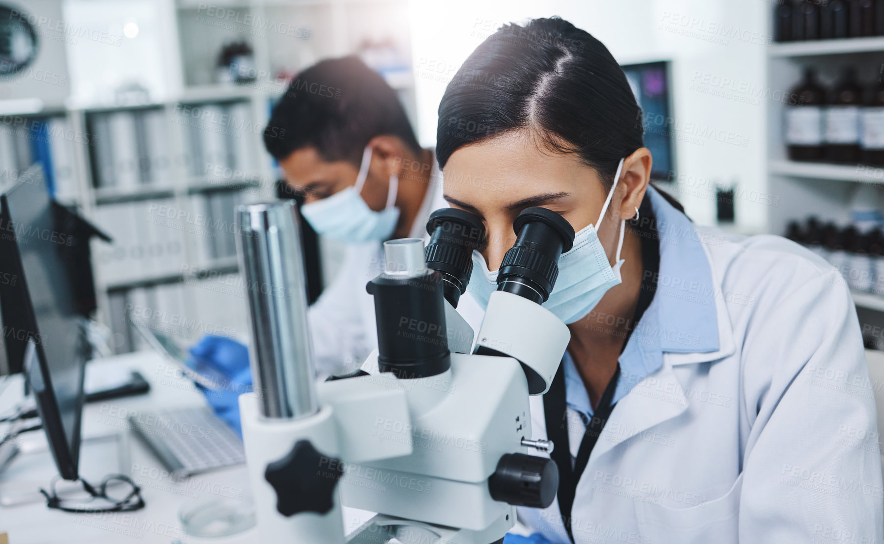 Buy stock photo Shot of two young researchers working in a laboratory