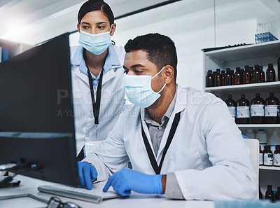 Buy stock photo Shot of two young researchers using a computer in a laboratory