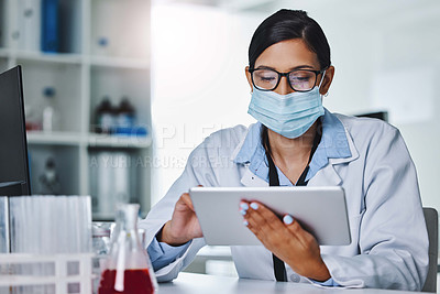 Buy stock photo Shot of a young female researcher using a digital tablet in an office at work
