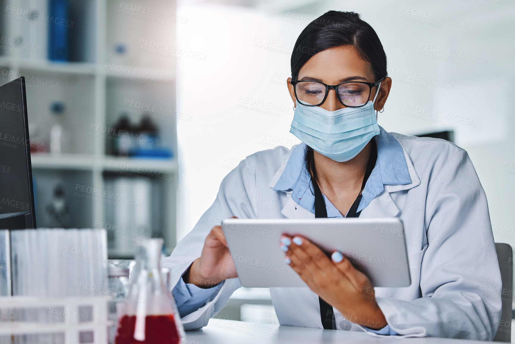 Buy stock photo Shot of a young female researcher using a digital tablet in an office at work