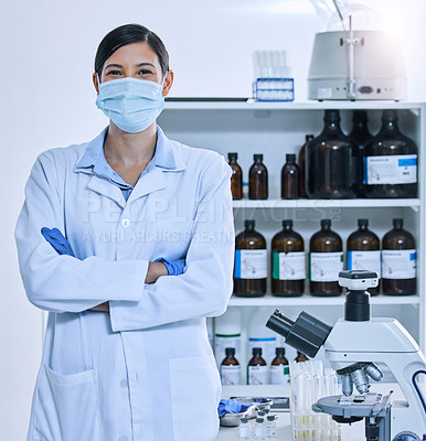 Buy stock photo Cropped portrait of a young female scientist wearing a mask while standing with her arms folded in her lab