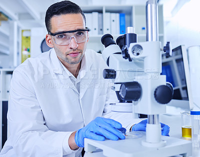 Buy stock photo Cropped portrait of a handsome young male scientist working on a microscope in his lab
