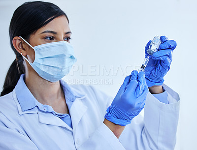 Buy stock photo Cropped shot of an attractive young female scientist using a syringe to extract the covid 19 vaccine from a bottle in her lab