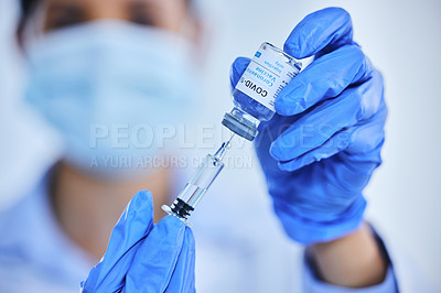 Buy stock photo Cropped shot of an unrecognizable female scientist using a syringe to extract the covid 19 vaccine from a bottle in her lab