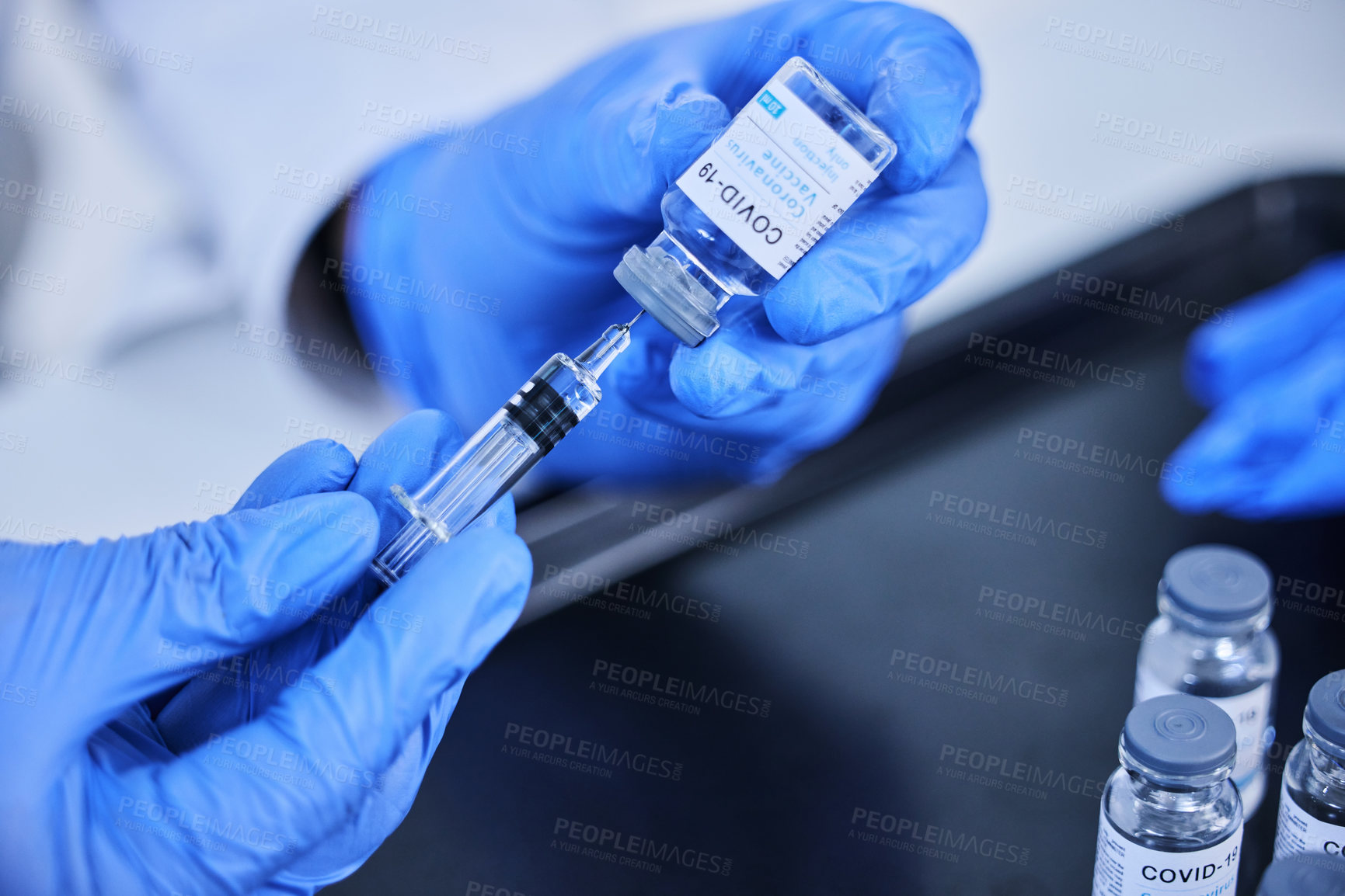 Buy stock photo Cropped shot of an unrecognizable scientist using a syringe to extract the covid 19 vaccine from a bottle in the lab