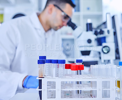 Buy stock photo Cropped shot of vials in a lab with an unrecognizable male scientist working in the background