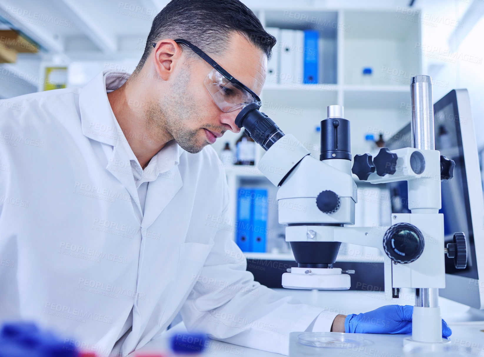 Buy stock photo Cropped shot of a handsome young male scientist working with a microscope in his lab