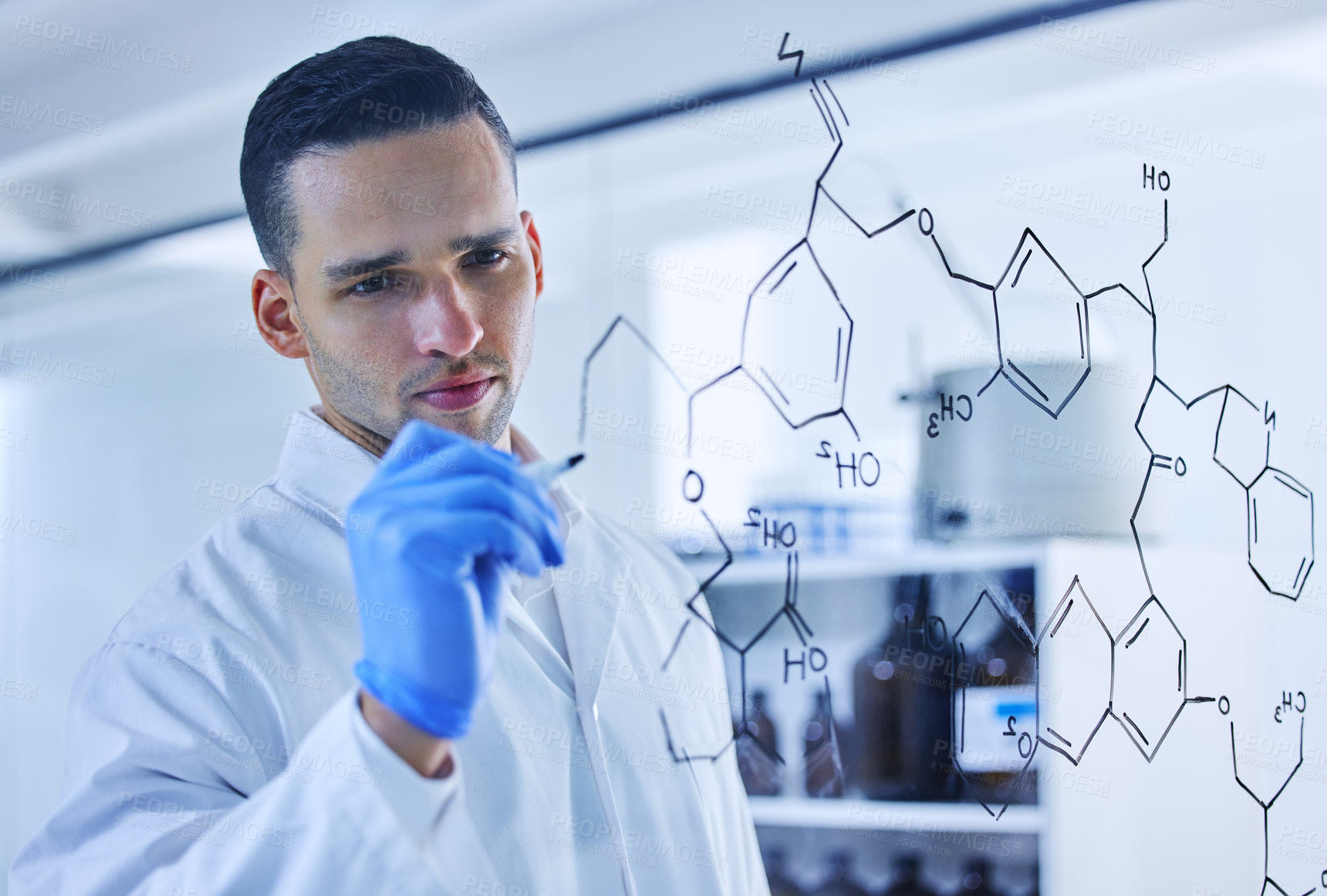 Buy stock photo Cropped shot of a handsome young male scientist working on a glass wipe board in his lab