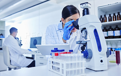 Buy stock photo Cropped shot of an attractive young female scientist working with a microscope and tablet in her lab