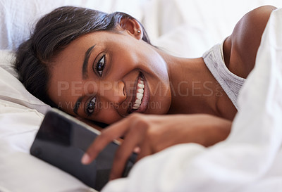 Buy stock photo Woman, phone and texting in morning, reading and wake up with smile for notification, chat or online dating in home. Girl, person and happy with smartphone, application and mobile network in bedroom