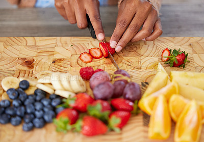 Buy stock photo Hands, fruit and cutting on board in kitchen, nutrition and fresh or raw food for detox in home. Fingers of person, knife and chopping organic ingredients for vegan diet, vitamins and minerals