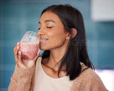 Buy stock photo Shot of a young woman drinking a healthy smoothie at home
