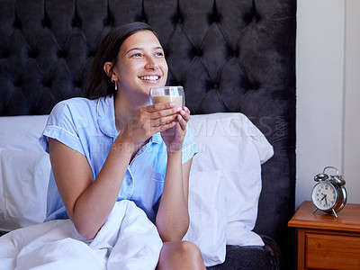 Buy stock photo Shot of a young woman drinking a glass of water in bed at home