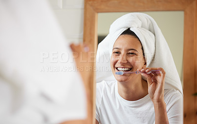 Buy stock photo Shot of a young woman brushing her teeth while looking into the bathroom mirror