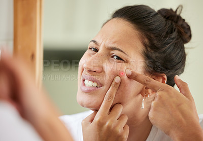 Buy stock photo Shot of a woman squeezing a pimple while looking into the bathroom mirror